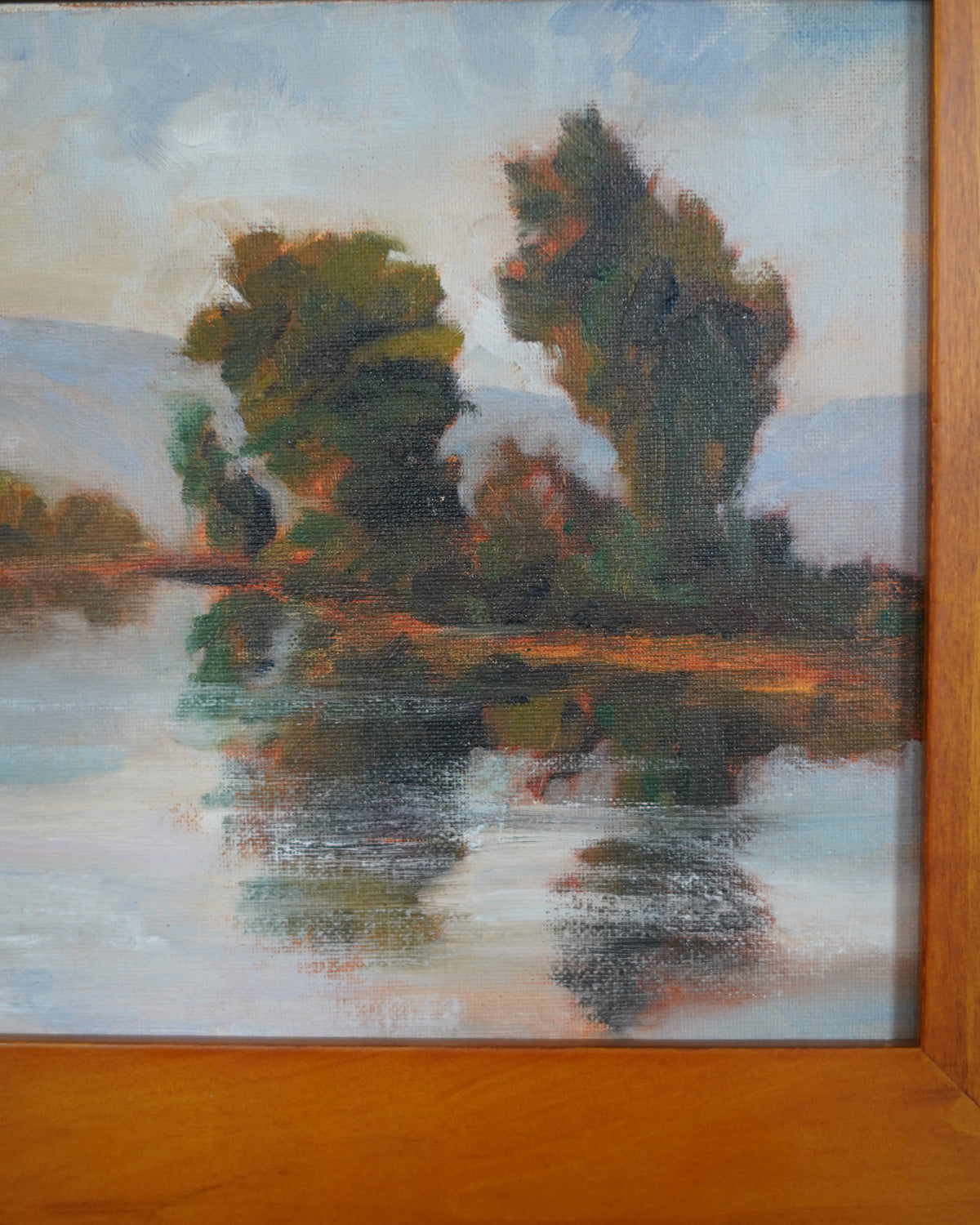 Oil painting of trees reflected in a lake with mountains, Peter Dann